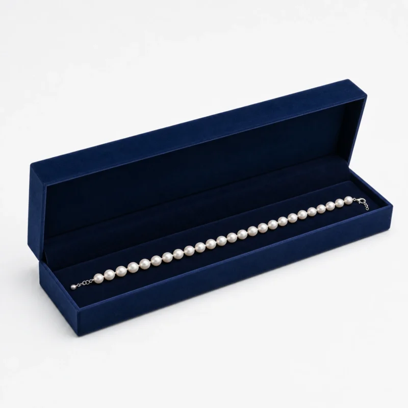 Open navy velvet necklace box with a white pearl necklace Open navy velvet necklace box with a white pearl necklace