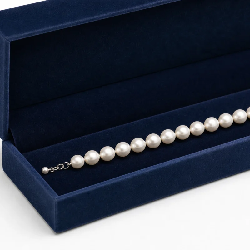 Close-up of a pearl necklace on the navy velvet box insert Close-up of a pearl necklace on the navy velvet box insert