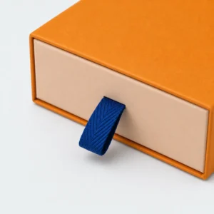 Blue woven pull tab and drawer front detail on an orange gift box