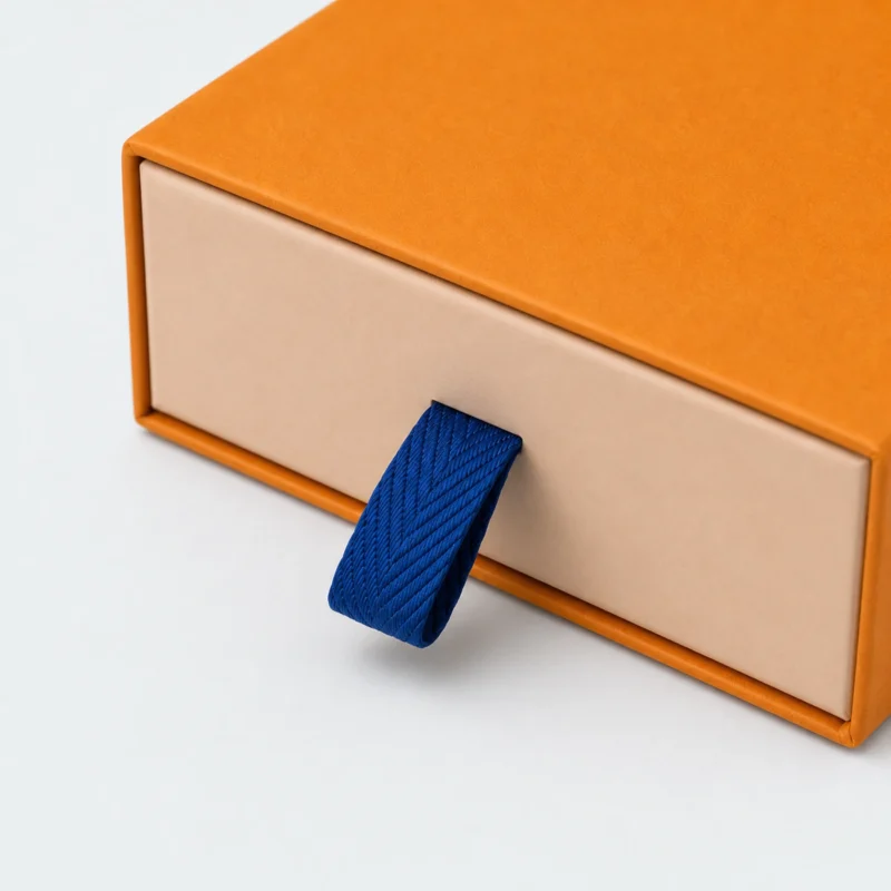 Blue woven pull tab and drawer front detail on an orange gift box