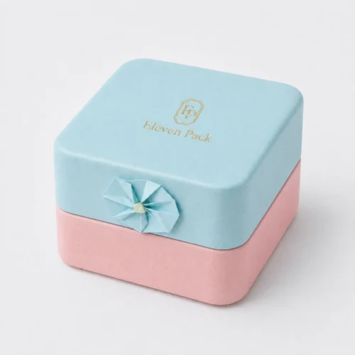 Closed pastel blue and pink jewelry box with a top gold logo and side paper flower