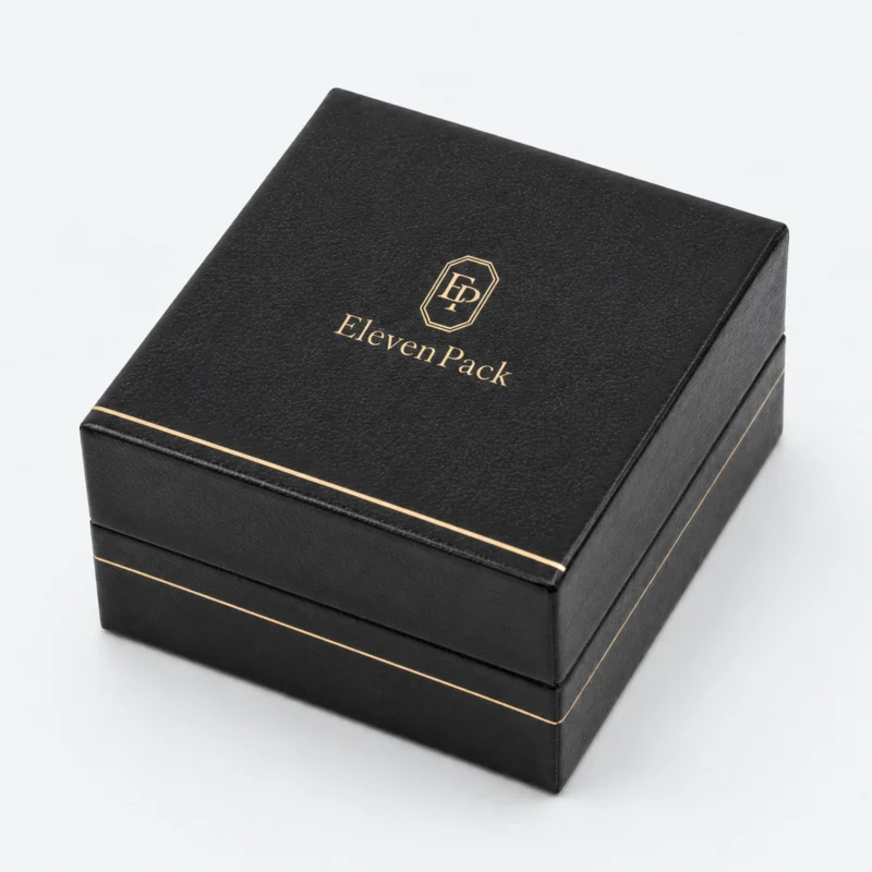 Closed black leather earring box with centered gold logo and trim Closed black leather earring box with centered gold logo and trim