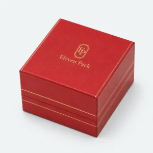 Closed custom red leather ring box with centered gold logo and trim