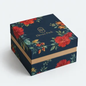 Closed navy floral paper gift box with gold band and logo