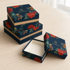 Three navy floral lid-and-base gift boxes on a pale wood table