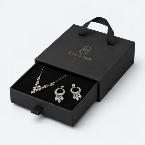 Open black cardboard drawer jewelry box with necklace and earrings