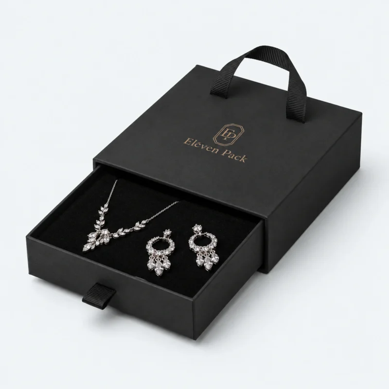 Open black cardboard drawer jewelry box with necklace and earrings