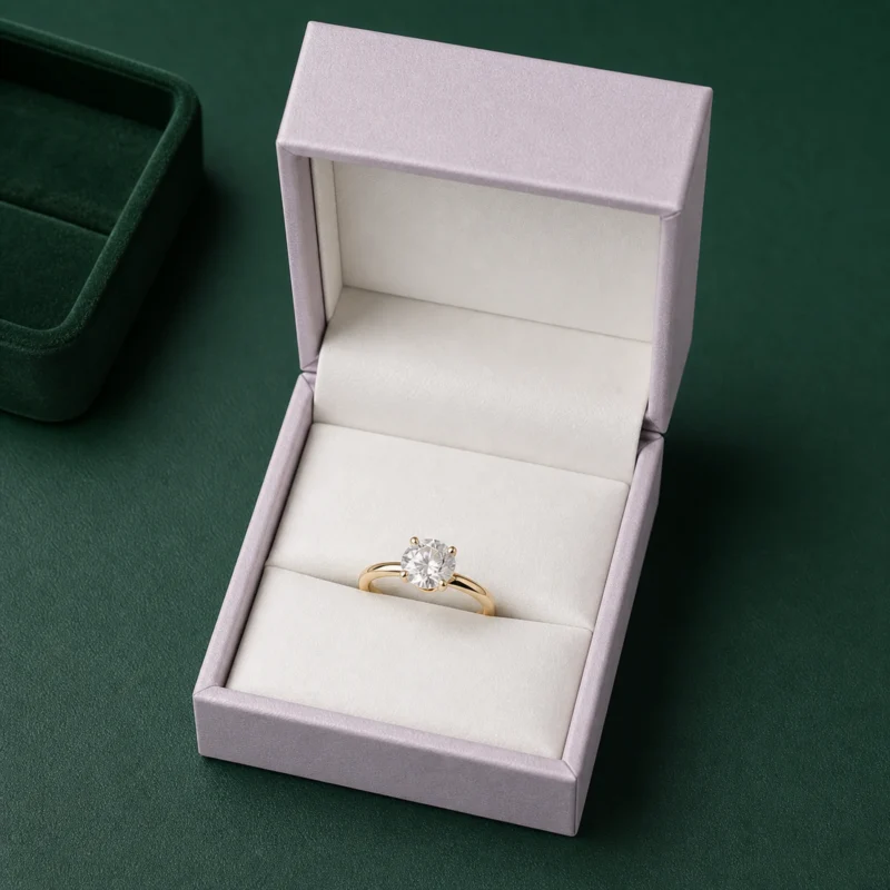 Pale lilac ring box on a dark green jewelry counter