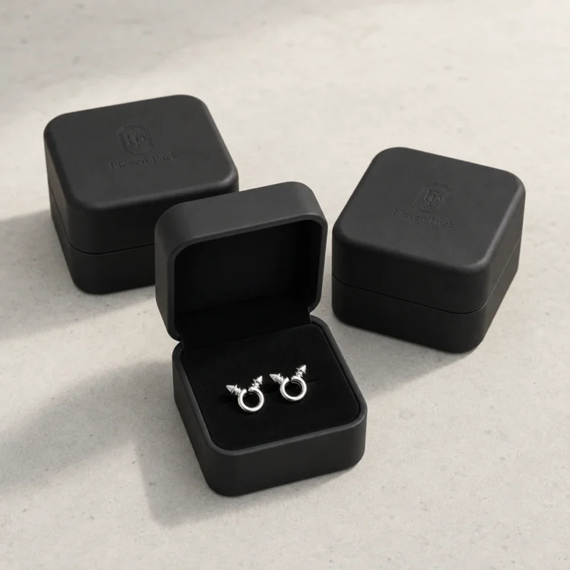 Three black rounded earring boxes on pale concrete