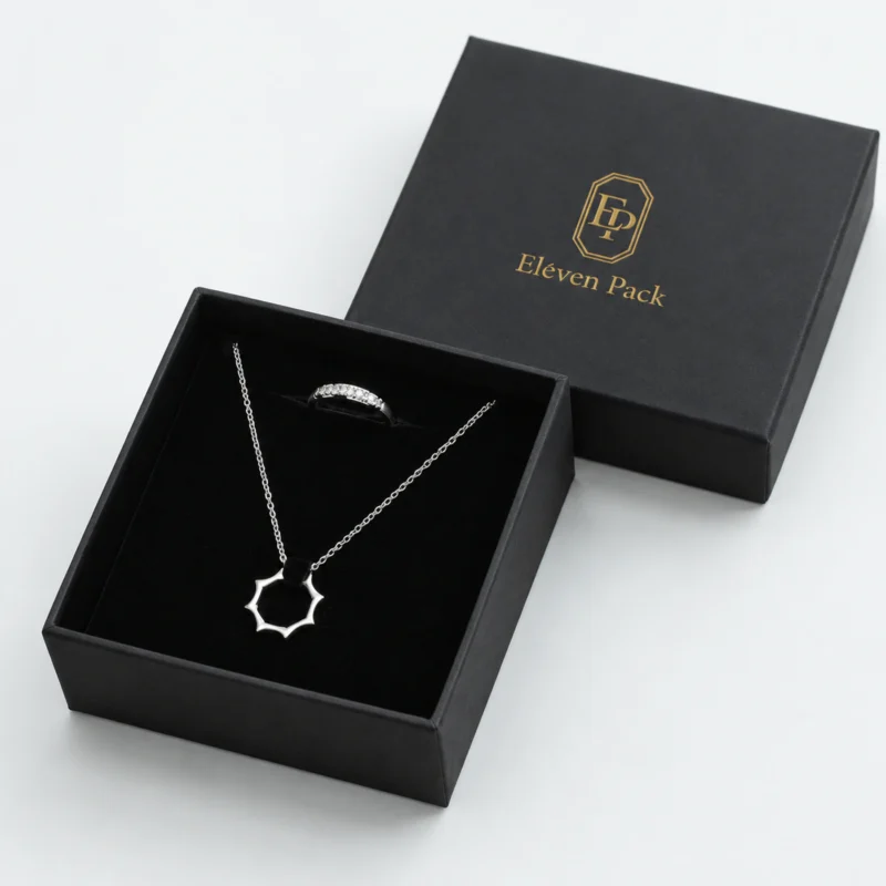 Open black cardboard necklace box with black velvet insert and matching branded lid