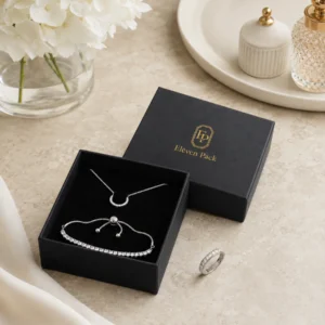 Black jewelry box displaying necklace and bracelet pieces in a styled packaging scene
