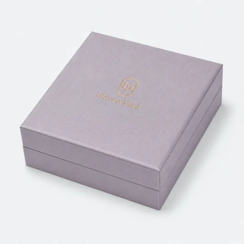 Closed gray lilac linen jewelry box with centered gold Eleven Pack logo