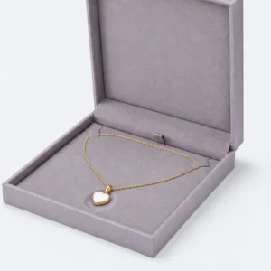 Close-up of two necklace tabs and heart pendant resting in a shallow padded recess