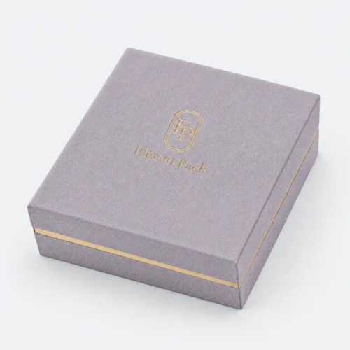 Closed lavender fabric hinged jewelry box with gold logo and perimeter band