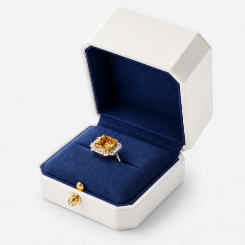 Open white leather ring box with blank navy lid and gemstone ring in the seam