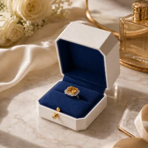 White and navy engagement ring box styled on a warm marble tabletop
