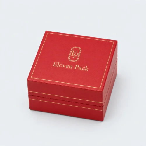 Closed square red leather ring box with gold trim and ElevenPack logo on the lid top