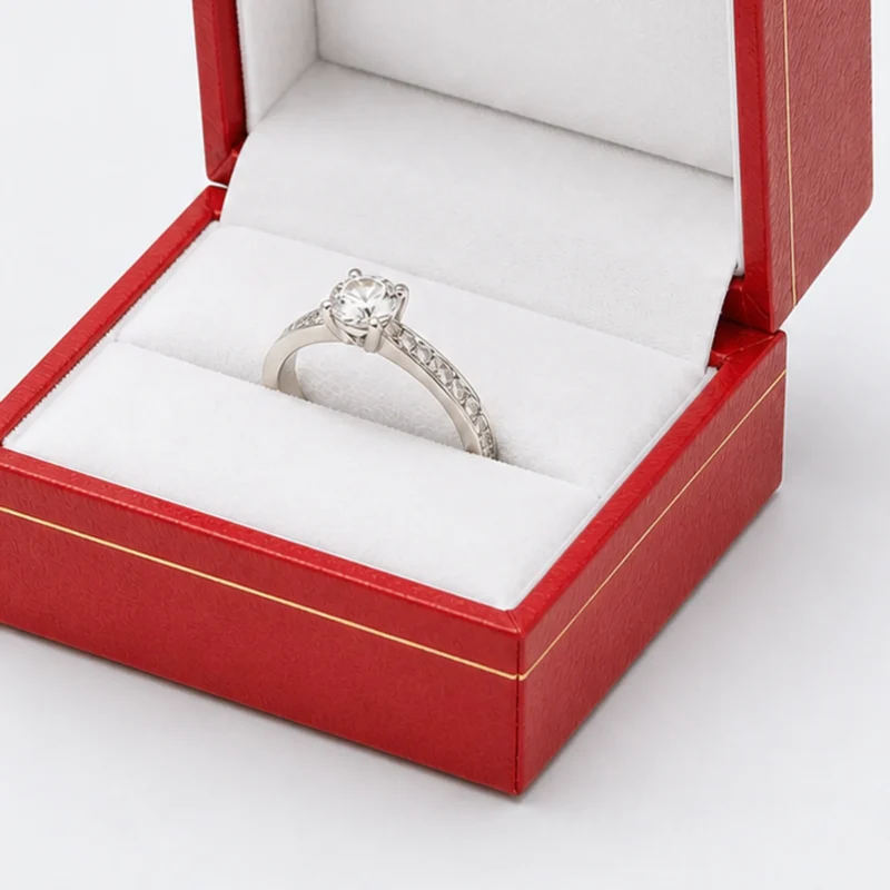 Close view of a ring seated in the padded seam of a square red leather ring box