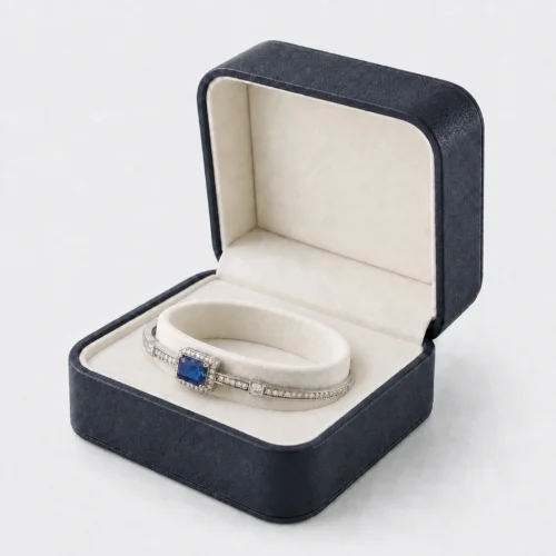 Open dark blue leather hinged bangle box with ivory annular cushion and gemstone bangle
